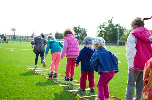 pexels-photo-296301-296301 Children enjoy an outdoor activity on a grassy field, stepping over a ladder.