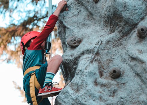 pexels-photo-3058762-3058762 Young child rock climbing with safety gear, showcasing courage and determination.