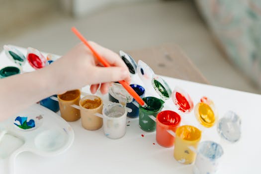 pexels-photo-6966323-6966323 A child paints using a colorful watercolor palette, fostering creativity and fun.